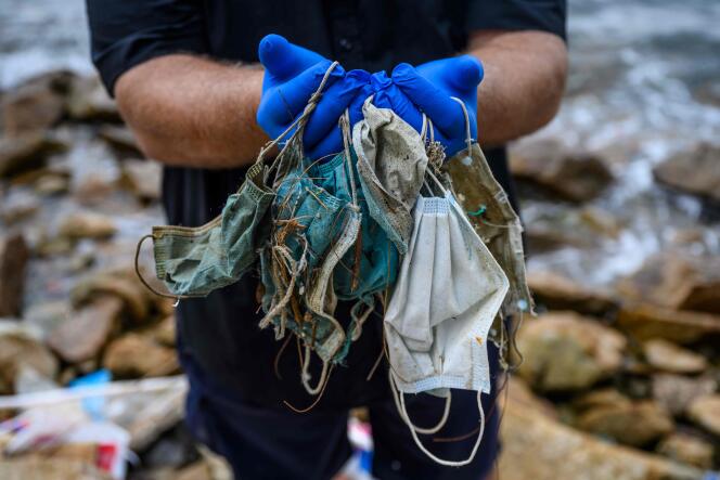 Le 13 mai 2020, Gary Stokes, fondateur du groupe environnemental Oceans Asia, pose avec des masques jetables abandonnés sur une plage de Discovery Bay, sur l’île périphérique de Lantau, à Hongkong.