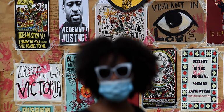 TOPSHOT - A demonstrator walks past a mural for George Floyd during a protest near the White House in Washington, DC, on June 4, 2020. On May 25, 2020, Floyd, a 46-year-old black man suspected of passing a counterfeit $20 bill, died in Minneapolis after Derek Chauvin, a white police officer, pressed his knee to Floyd's neck for almost nine minutes. / AFP / Olivier DOULIERY
