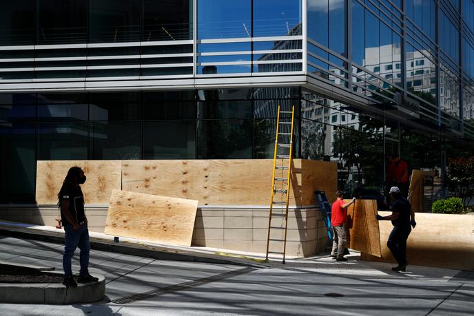 Des ouvriers du bâtiment protègent la façade d’un immeuble avant le passage de manifestants, à Washington, le 31 mai.