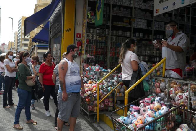 Un employé vérifie la température d’une cliente au premier jour de la réouverure des commerces à Sao Paulo au Brésil, mercredi 10 juin.