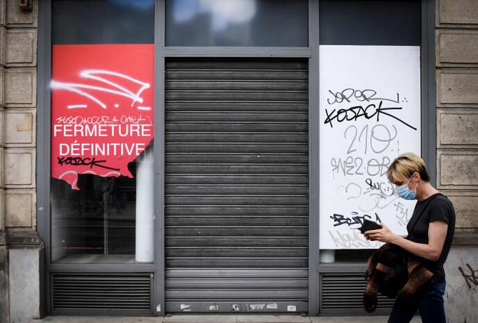 Une personne portant un masque de protection passe devant une boutique fermée, à Paris, le 8 juin.