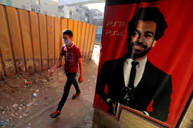 Un homme portant un masque de protection passe à côté d’une affiche représentant le footballeur égyptien Mohamed Salah, au Caire, le 18 mai 2020.