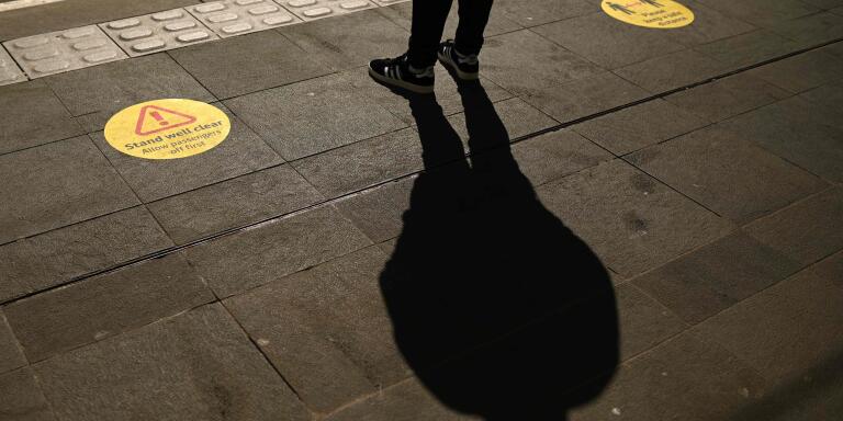 TOPSHOT - A man waits between markers advising commuters on social distancing on a tram platform in central Manchester on June 5, 2020, as lockdown measures are eased during the novel coronavirus COVID-19 pandemic. Face coverings will soon be compulsory for people wanting to travel on public transport in England to limit the spread of coronavirus. / AFP / Oli SCARFF
