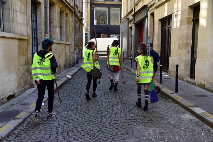 De jeunes adultes parcourent les rues de Bordeaux pour nettoyer celles-ci dans le cadre du projet « travail alternatif payé à la journée », en 2018.