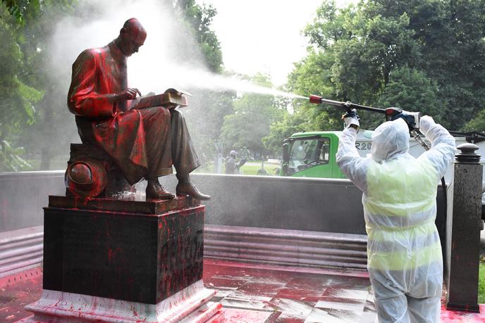 Un operaio comunale, pulisce la statua del giornalista Indro Montanelli, a Milano, nel giardino dello stesso nome, il 14 giugno del 2020.