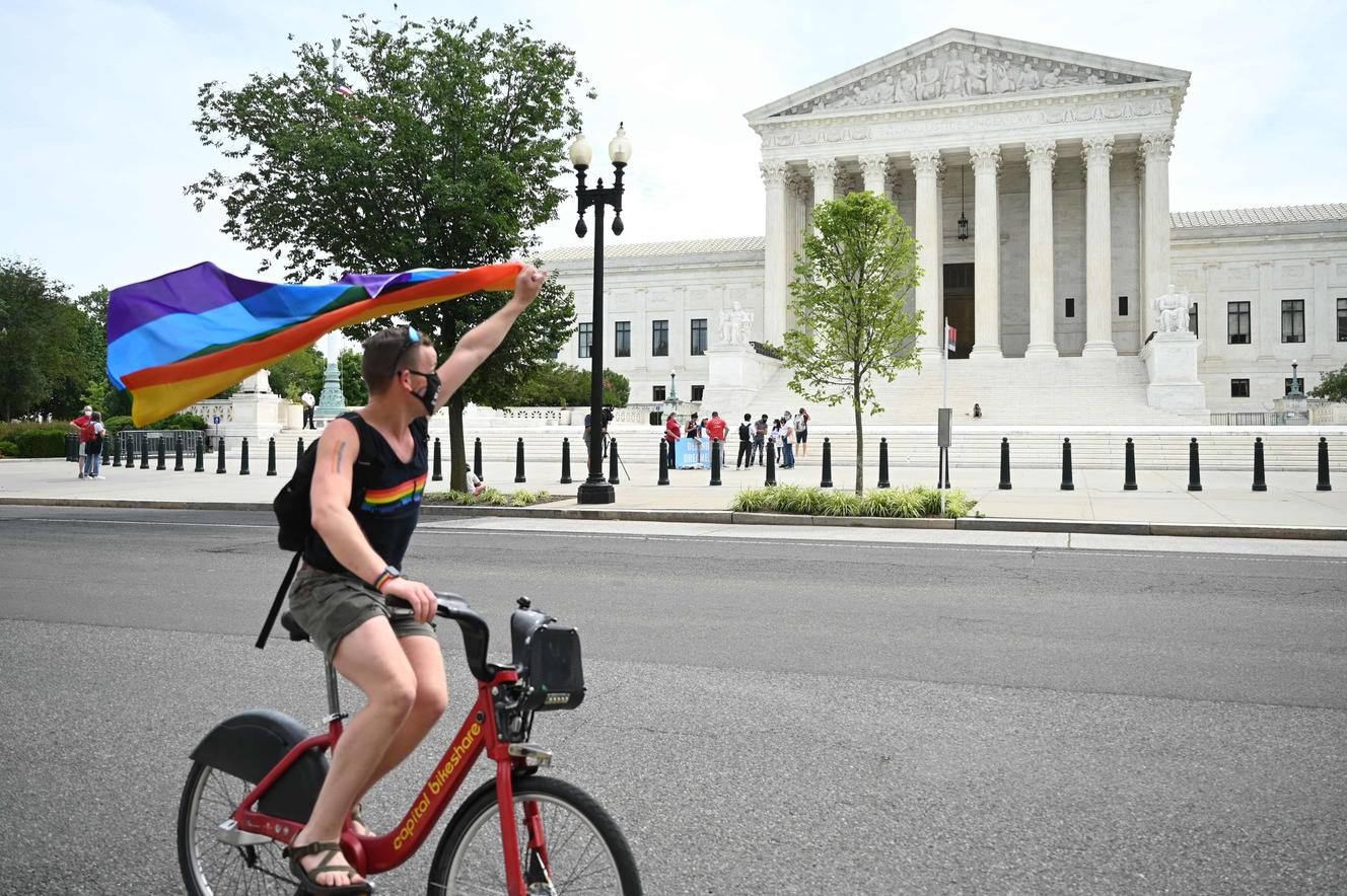 Un uomo brandish una bandiera arcobaleno in Parte anteriore della Corte Suprema degli Stati Uniti, lunedì 15 giugno.