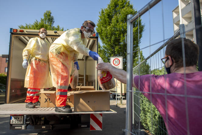 Après la découverte de nombreux cas de Covid-19 au sein de l’abattoir de Tönnies de Gütersloh (Rhénanie-du-Nord-Westphalie), des bénévoles de la Croix-Rouge distribuent du pain aux résidents de Verl, en proche banlieue, mise en quarantaine. Allemagne, dimanche 21 juin 2020.