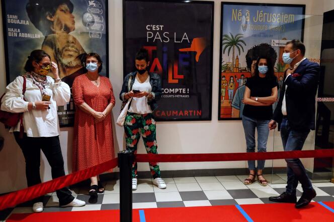 Des spectateurs masqués dans une file d’attente au cinéma 5 Caumartin à Paris, pour la réouverture des salles, le 21 juin au soir.
