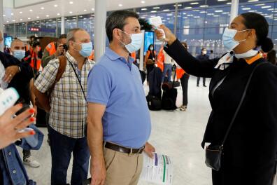 A stewardess takes the body temperature of a man before boarding a plane at Paris-Orly Airport on its re-opening day following the coronavirus disease (COVID-19) outbreak in France, June 26, 2020. REUTERS/Charles Platiau