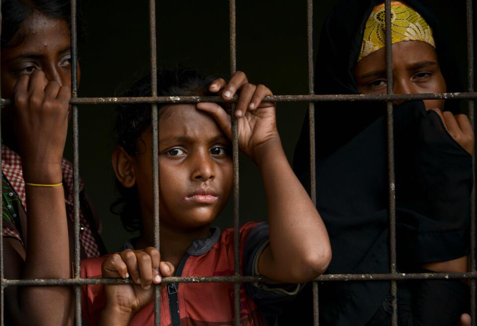 In this photo taken on June 26, 2020, Rohingya people from Myanmar look outside a fence at the immigration detention centre in Lhokseumawe, in Indonesia's North Aceh Regency. A group of Rohingya asylum seekers say they were beaten by traffickers and drank their own urine to stay alive on a perilous four-month journey at sea until their dramatic rescue near the Indonesian coast this week. - TO GO WITH: Indonesia-Myanmar-Bangladesh-migration-Rohingya-virus, FOCUS by Sarina / AFP / CHAIDEER MAHYUDDIN / TO GO WITH: Indonesia-Myanmar-Bangladesh-migration-Rohingya-virus, FOCUS by Sarina