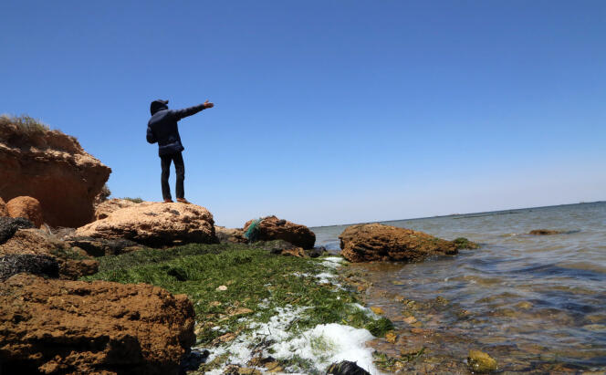 Un homme pointe l’horizon sur une île des Kerkennah, en Tunisie, en juin 2018. L’archipel est un haut lieu de départ de migrants vers l’Italie.