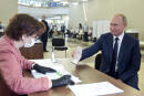 Russian President Vladimir Putin shows his passport to a member of an election commission as he arrives to take part in voting at a polling station in Moscow, Russia, Wednesday, July 1, 2020. The vote on the constitutional amendments that would reset the clock on Russian President Vladimir Putin's tenure and enable him to serve two more six-year terms is set to wrap up Wednesday. (Alexei Druzhinin, Sputnik, Kremlin Pool Photo via AP)