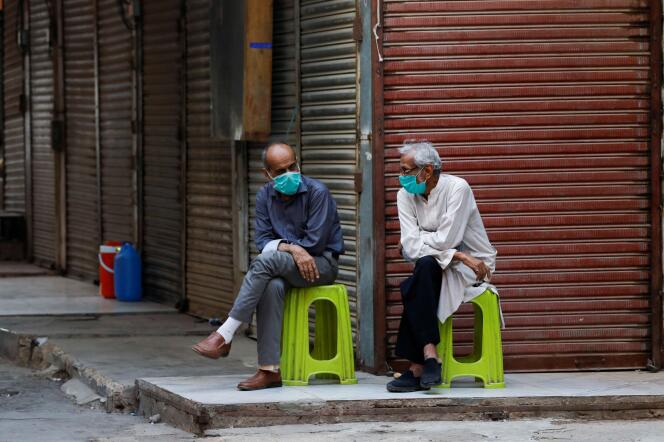 Des commerçants, portant des masques de protection, devant leurs boutiques fermées, à Karachi, au Pakistan, le 1er juillet. Les autorités ont réimposé des mesures de confinement dans certaines zones du pays afin d’endiguer la propagation du coronavirus SARS-CoV-2.