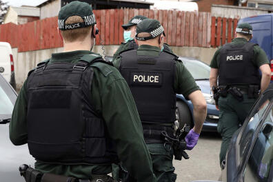 In this photo issued Thursday July 2, 2020, by the Police Service of Northern Ireland (PSNI) showing police during a raid in Operation Venetic, an investigation on Encrochat, a military-grade encrypted communication system used by organised criminals trading in drugs and guns. Police have released information saying that officers in the UK had arrested 307 suspects, recovered 106 Encrochat devices and seized many millions in bank notes. (PSNI via AP)
