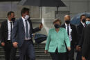 German Chancellor Angela Merkel, center, walks under an umbrella as she leaves after addressing a plenary session at the European Parliament in Brussels, Wednesday, July 8, 2020. Germany has just taken over the European Union's rotating presidency, and must chaperone the 27-nation bloc through a period of deep crisis for the next six months and try to limit the economic damage inflicted by the coronavirus. (AP Photo/Francisco Seco)