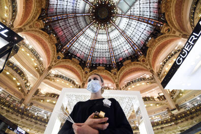 An employee wearing a protective mask, waits for customers at the Galeries Lafayette on the first day of the reopening of the luxury general store, on May 30, 2020, in Paris, as France eases lockdown measures taken to curb the spread of the Covid-19 pandemic (novel coronavirus). (Photo by ALAIN JOCARD / AFP)