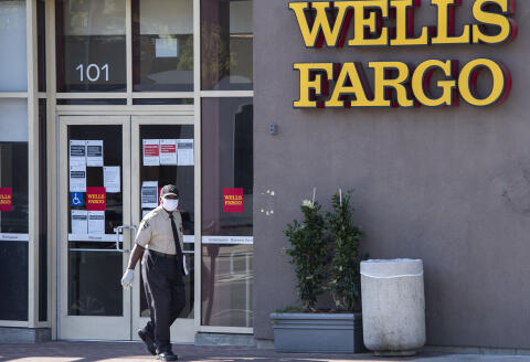 A security guard wearing mask and gloves walks outside a branch of the Wells Fargo bank, amid the novel coronavirus pandemic, on May 15, 2020, in West Hollywood, California. (Photo by VALERIE MACON / AFP)