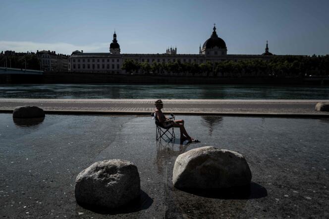 Un homme se rafraîchit, assis dans un bassin du centre de Lyon, le 30 juillet.
