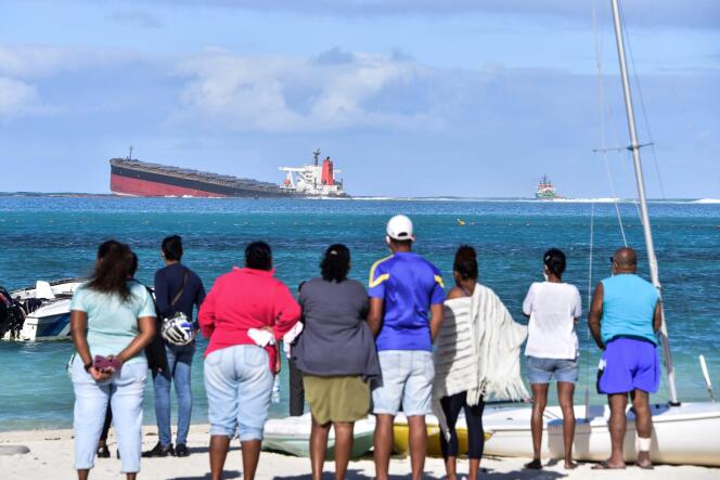 Des passants observent le vraquier Wakashio échoué dans l’océan Indien, au sud-est de l’île Maurice, le 6 août.