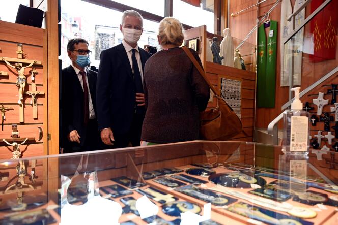 Le ministre de l’économie et des finances, Bruno Le Maire (au centre), visite une boutique de souvenirs près du sanctuaire de Notre-Dame de Lourdes, le 10 août, dans le sud-ouest de la France.