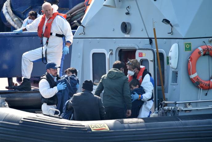 Les agents des forces frontalières britanniques aident les migrants avec des enfants, dans le port de Douvres, sur la côte sud-est de l’Angleterre, le 9 août .