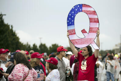 FILE - In this Aug. 2, 2018, file photo, a protesters holds a Q sign waits in line with others to enter a campaign rally with President Donald Trump in Wilkes-Barre, Pa. Facebook says on Wednesday, Aug. 19, 2020, it will restrict QAnon and stop recommending that users join groups supporting it, but the company is stopping short of banning the right-wing conspiracy movement outright. (AP Photo/Matt Rourke, File)