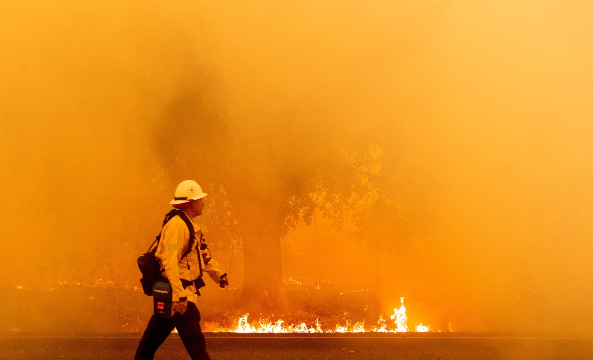 Un pompier marche devant un mur de feu, sur une route de Fairfield, en Californie, le 19 août.
