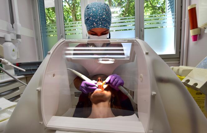 Une dentiste soigne un patient, derrière une protection en Plexiglass, à Toulouse, le 7 juillet.