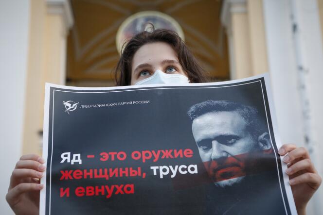 Jeudi 20 août, une manifestante tient une affiche sur laquelle on peut lire « Le poison est l’arme d’une femme, d’un lâche et d’un eunuque » lors d’un piquet de soutien au leader de l’opposition russe, Alexeï Navalny, dans le centre de Saint-Pétersbourg, en Russie.
