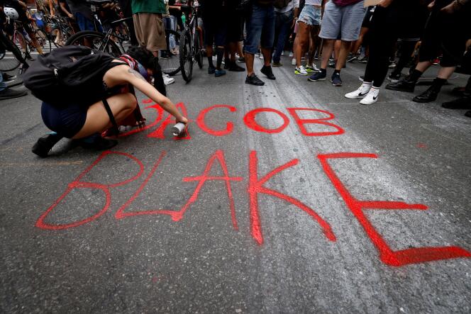 A New York, une femme peint sur la chaussée le nom de Jacob Blake, un homme noir grièvement blessé par des policiers blancs dans le Wisconsin, le 24 août.