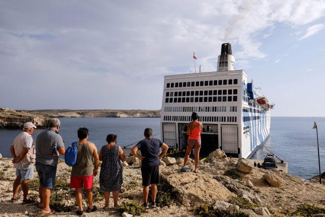 Des touristes, devant un bateau de migrants en quarantaine, le 4 août à Lampedusa (Italie).