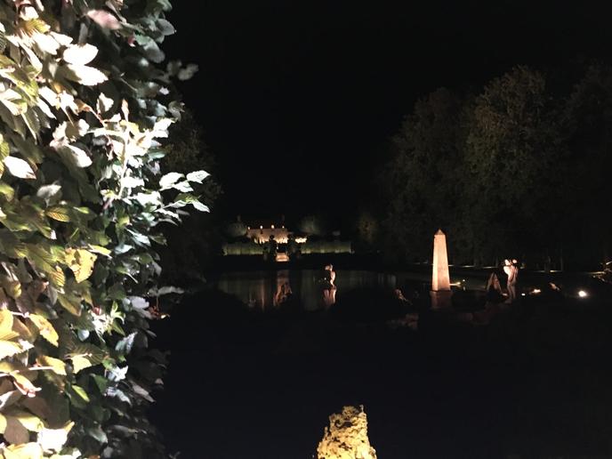 Vue nocturne du miroir d’eau, depuis les colonnades de verdure.