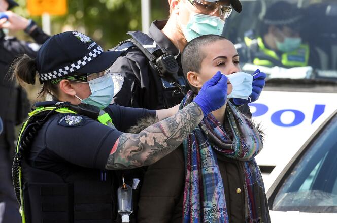 Une policière place un masque sur le visage d’une manifestante arrêtée à Melbourne, samedi 5 septembre, durant une manifestation anticonfinement.