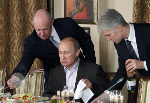 FILE - In this Friday, Nov. 11, 2011, file photo, businessman Yevgeny Prigozhin, left, serves food to Russian Prime Minister Vladimir Putin, center, during dinner at Prigozhin's restaurant outside Moscow, Russia. The U.S. sought to punish Russia on Monday, Sept. 30, 2019, for interfering with the November 2018 election by placing the yacht and private planes of a Russian financier, Yevgeny Prigozhin, on an international sanctions list along with employees of the Internet Research Agency that he has funded to spread false information on social media. (AP Photo/Misha Japaridze, Pool, File)