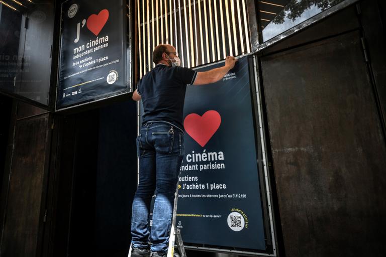 STÉPHANE DE SAKUTIN/AFP An employee removes movie posters outside The Max Linder Cinema Theatre in Paris on June 18, 2020, ahead of the re-opening of cinema halls and theatres, as France eases lockdown measures taken to curb the spread of the Covid-19 pandemic (novel coronavirus). (Photo by STEPHANE DE SAKUTIN / AFP)