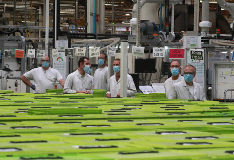 Employees, wearing protective face masks, look on at a factory of manufacturer Valeo in Etaples, near Le Touquet, northern France on May 26, 2020 during a visti of French President as part of the launch of a plan to rescue the French car industry. (Photo by Ludovic MARIN / POOL / AFP)