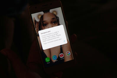 An emergency alert message displaying the citywide curfew is seen on a woman's phone a day after a grand jury decided not to bring homicide charges against police officers involved in the fatal shooting of Breonna Taylor in her apartment, in Louisville, Kentucky, U.S. September 24, 2020. REUTERS/Lawrence Bryant