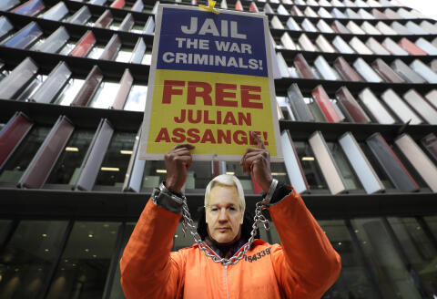 A demonstrator holds a banner and wears a Julian Assange mask opposite the Old Bailey in London, Thursday, Oct. 1, 2020, as the Julian Assange extradition hearing to the US continues. (AP Photo/Kirsty Wigglesworth)