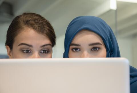 Close-up of two female colleagues working on a laptop