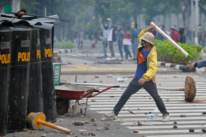 Des militants lancent des projectiles contre la police, lors d’affrontements contre une nouvelle loi qui devrait favoriser les investisseurs au détriment des droits du travail et de l’environnement, à Djakarta, le 8 octobre 2020.