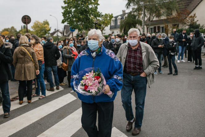 Des habitants affluent avec des bouquets de fleurs pour rendre hommage au professeur assassiné, à Conflans-Sainte-Honorine, le 17 octobre.