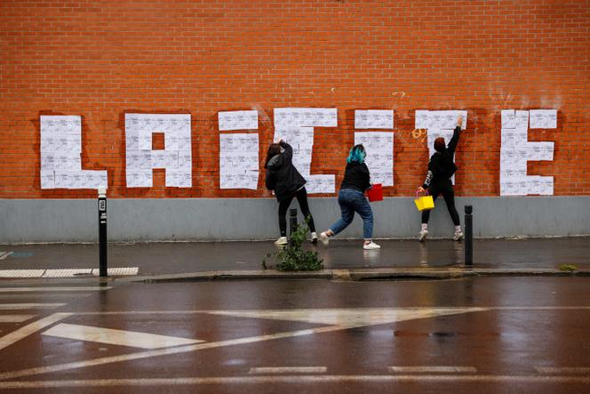 Trois activistes féministes placardent des affiches d’un dessin de Charb pour former le mot « Laïcité » à Montreuil, octobre 2020.