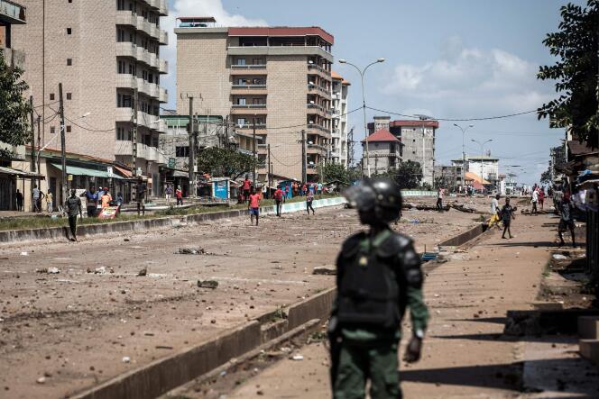 Ce 23 octobre à Conakry, capitale de la Guinée, un policier regarde un manifesteant qui jette des pierres.  / AFP / JOHN WESSELS