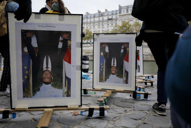 Des militants d’ANV-COP21 (Action non violente-COP21) attachent des portraits à l’envers d’Emmanuel Macron, sur les quais de la Seine, à Paris, le 15 octobre 2020. Ils soutiennent ainsi les « décrocheurs », six activistes d’Action climat Paris, du portrait d’Emmanuel Macron dans des mairies parisiennes.