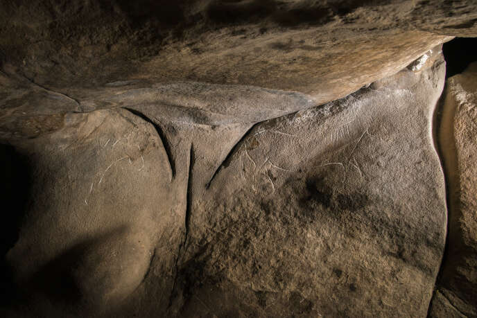 Les trois profondes entailles, en partie créées par l’homme au paléolithique supérieur, entourées de deux chevaux.