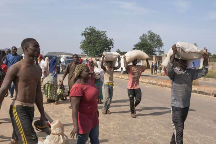 Des gens portant des sacs de nourriture sur la tête lors du pillage d’un entrepôt où sont stockées des denrées alimentaires amassées pendant le confinement et qui n’ont pas été distribuées à la population à Jos, au Nigeria, le 24 octobre.