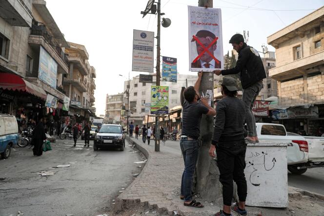 Des hommes fixent une pancarte condamnant le président français Emmanuel Macron pour ses commentaires sur les caricatures du prophète Mahomet dans la ville d’Idlib, dans le nord-ouest de la Syrie, tenue par les rebelles le 25 octobre.