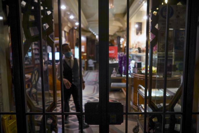 Un membre du personnel se tient derrière les barreaux d’un restaurant fermé, à Rome, lundi 26 octobre 2020.