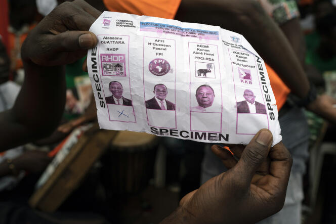Un militant montre un bulletin de vote en faveur du président ivoirien Alassane Ouattara, sur lequel figurent aussi les candidats de l’opposition, lors d’un rassemblement à Anyama, dans la banlieue d’Abidjan, le 28 octobre 2020.