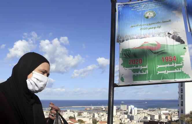 Une femme marche devant des affiches promouvant le vote pour le prochain référendum, à Alger, le 27 octobre.